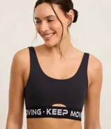 Top deportivo negro de microfibra con breteles anchos, copas desmontables, recorte cut-out en el busto y banda elástica con estampado de letras "Keep Moving".
