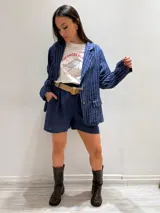 Blazer azul marino con rayas verticales blancas, confeccionado en lino italiano. Tiene botones de coco, solapas clásicas y bolsillos delanteros.