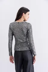 Remera negra de mangas largas con lentejuelas aplicadas en toda la prenda, escote redondo y forrería interna.