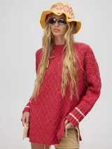 Sweater color crema con tejido en ochos, cuello redondo, puños acanalados con doble raya azul y tajos a los costados.