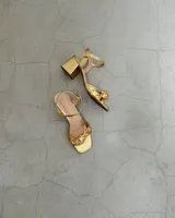 Sandalia plateada de cuero vacuno con taco cuadrado de 6 cm y tira delantera con nudo.
