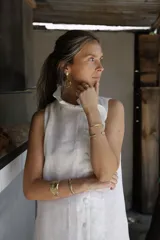 Vestido corto blanco de lino, musculosa con volado en cuello y acceso frontal cruzado. Abotonadura forrada en lino.
