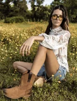 Botas cortas negras de cuero con bordados blancos estilo cowboy.