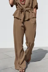 Pantalón marrón de tiro alto con cintura elástica, bolsillos delanteros y pernera ancha.