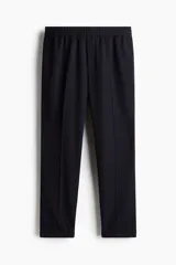 Pantalón tobillero azul marino de sarga suave con cintura elástica y cordón ajustable. Tiene bolsillos laterales y traseros ribeteados, piernas con pliegues cosidos y doblez en el bajo.