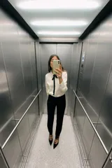 Camisa color crema de satén con cuello solapa, manga larga y lazo negro contrastante. Cierre frontal con botones.