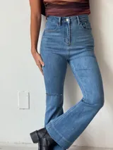 Pantalón de jean azul de tiro alto, corte semioxford y detalle de rotura en la rodilla.
