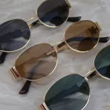 Lentes de sol con marco dorado y lentes ovaladas negras.