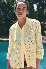 Camisa amarilla de cuello solapa y manga larga acabada en puño. Detalle de bordados perforados a tono. Cierre frontal con botones ocultos por solapa.