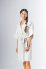 Bata kimono corta color beige, confeccionada en tela waffle de algodón. Tiene mangas al codo, lazo de ajuste en la cintura y detalle de vivo en la solapa.