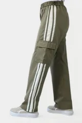 Pantalón negro de corte ancho con cintura elastizada y cordón ajustable. Presenta una franja vertical blanca a lo largo de la pierna y un bolsillo tipo cargo en el muslo.