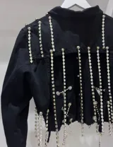 Campera cropped de jean negra con tiras de strass plateado y botones plateados al frente.