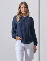 Blusa azul marino de manga larga con cuello redondo con detalle de broderie y cierre frontal con botones.