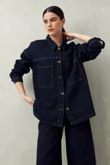 Sobrecamisa oversize de jean azul con cuello camisero, cierre frontal con botones, mangas largas y bolsillos de parche en el pecho.