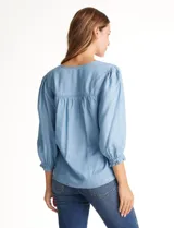 Blusa de lyocell color azul claro, con escote en V, detalles de costuras verticales en el frente y mangas tres cuartos con puños elastizados.