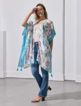 Kimono tejido con estampado floral multicolor, terminación de ruedo con borlas y mangas cortas con borde celeste.