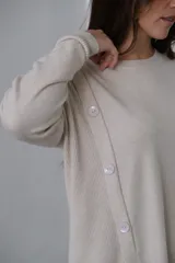 Sweater beige de punto, corte recto, cuello redondo y detalle de botones en el lateral.
