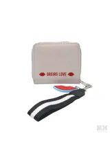 Billetera tipo monedero de color celeste claro, con cierre de cremallera y detalle frontal con texto 'MON AMOUR' en un parche blanco. Incluye un llavero desmontable con forma de labios rojos y una correa de mano negra con franjas blancas.