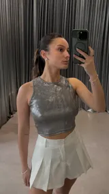 Top plateado brillante sin mangas, de corte cropped y cuello redondo.