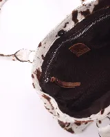 Cartera baguette de cuero con estampado animal print de vaca en tonos marrón y blanco. Tiene forro interior, un bolsillo amplio y broches laterales para ajustar el tamaño.