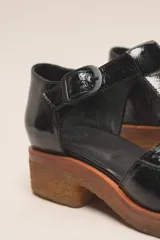 Zapato guillermina de cuero vacuno charol color negro, con suela de goma color marrón.