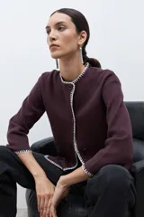 Saco de punto color ciruela oscuro, de manga larga y cuello redondo, con cierre frontal de botones y ribetes en contraste blanco con puntada decorativa.