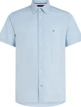 Camisa celeste de mangas cortas, confeccionada en popelín de puro algodón. Tiene cuello abotonado, bajo redondeado y logo de Tommy Hilfiger bordado en el pecho.