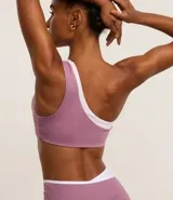 Top deportivo de microfibra color lila con detalle bicolor blanco, hombro único, escote asimétrico y gota vazada.