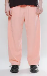 Pantalón de corte sastrero color salmón, de tela suede suave y holgada, con bolsillos laterales, cintura trasera elástica ajustable y cierre frontal con botón.