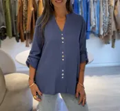 Blusa azul jeans de manga larga regulable, con escote en pico y botones en la parte delantera.