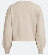 Cardigan corto de punto color crema, con escote en V, abotonadura frontal y mangas largas abullonadas con puños acanalados. Presenta un punto calado en forma de rombos en la parte superior del busto y en las mangas.