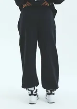 Pantalón de jogging negro de frisa esmerilada con cintura y botamanga elastizada, cordones de algodón con puntera termocontraíble y bolsillos laterales.