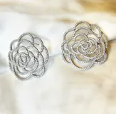 Par de aros rígidos con forma de flor calada, con incrustaciones de circonias.