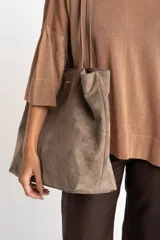 Bolso tipo tote de gamuza vegana color camel, con asas de mano y logo grabado en el frente.
