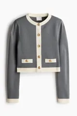 Cárdigan corto gris de punto fino con cuello redondo, cierre frontal con botones metálicos dorados y bolsillos decorativos con botón.