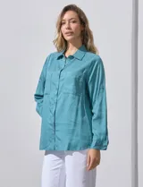 Camisa blanca de lyocell, marca Dash. Tiene cuello con solapa, abertura central con botones, mangas largas regulables con presilla y botón, y dos bolsillos delanteros aplicados.