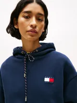 Buzo azul marino amplio con capucha y cordón distintivo, bolsillo canguro, puños y bajo de punto canalé, logo oversize de Tommy Hilfiger en la manga y la parte trasera, parche con logo de Tommy Hilfiger en el pecho y detalles distintivos de Hilfiger Sailing.