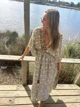 Vestido largo de seda color crema con estampado geométrico en tonos camel y negro. Tiene escote en V, mangas cortas amplias y cintura ajustable con cordón.