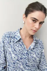 Camisa de manga larga con estampado paisley en tonos azul y blanco, cuello camisero y cierre frontal con botones.