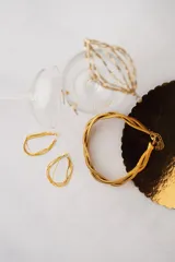 Aros colgantes dorados con forma de gota, compuestos por múltiples cadenas finas entrelazadas.