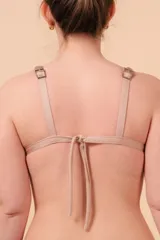 Corpiño de bikini negro con vivos color beige, de corte triangular sin aro, con breteles regulables y nudo en la espalda.