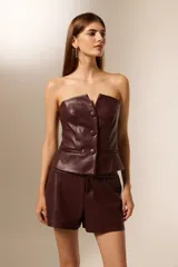 Top sin mangas de cuero sintético color borgoña, con cuello strapless, pinzas en el busto y cierre frontal con tres botones grandes.
