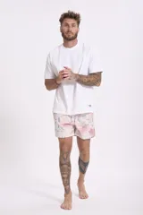 Short de baño con estampado de flores de loto y hojas en tonos amarillo, naranja y verde sobre fondo azul.