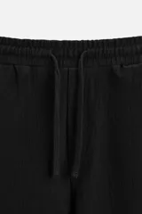Bermuda negra de corte relaxed fit, con cintura elástica ajustable con cordón, bolsillos frontales y bolsillo trasero de parche.