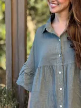 Vestido camisero azul de lino italiano, con cuello camisero, botones frontales, mangas 3/4 con doble volado y bolsillos laterales.