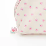 Neceser de tela color crema con estampado de pequeñas flores rosas y celestes. Tiene forma redondeada, cierre superior con cremallera y tirador con forma de flor.