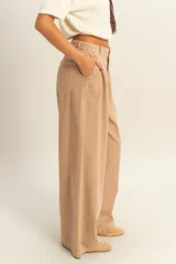 Pantalón color beige de corte ancho y tiro alto, con pinzas en la cintura y bolsillos laterales.