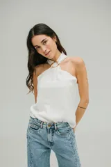 Blusa blanca de crepe twill con cuello halter y detalle de hebilla dorada en el escote.