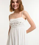 Vestido midi blanco con tirantes finos y escote cuadrado. Presenta bordados de caracolas en el busto y lazo en la espalda.