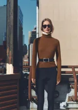 Sweater color beige de tejido de punto con cuello alto y mangas largas.